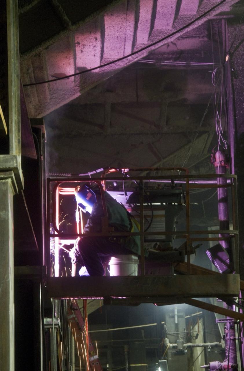 A welder at work, sparks lighting a dark workshop